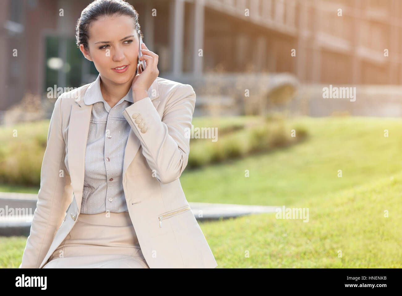 Bella giovane imprenditrice a conversare al telefono cellulare mentre guarda lontano Foto Stock