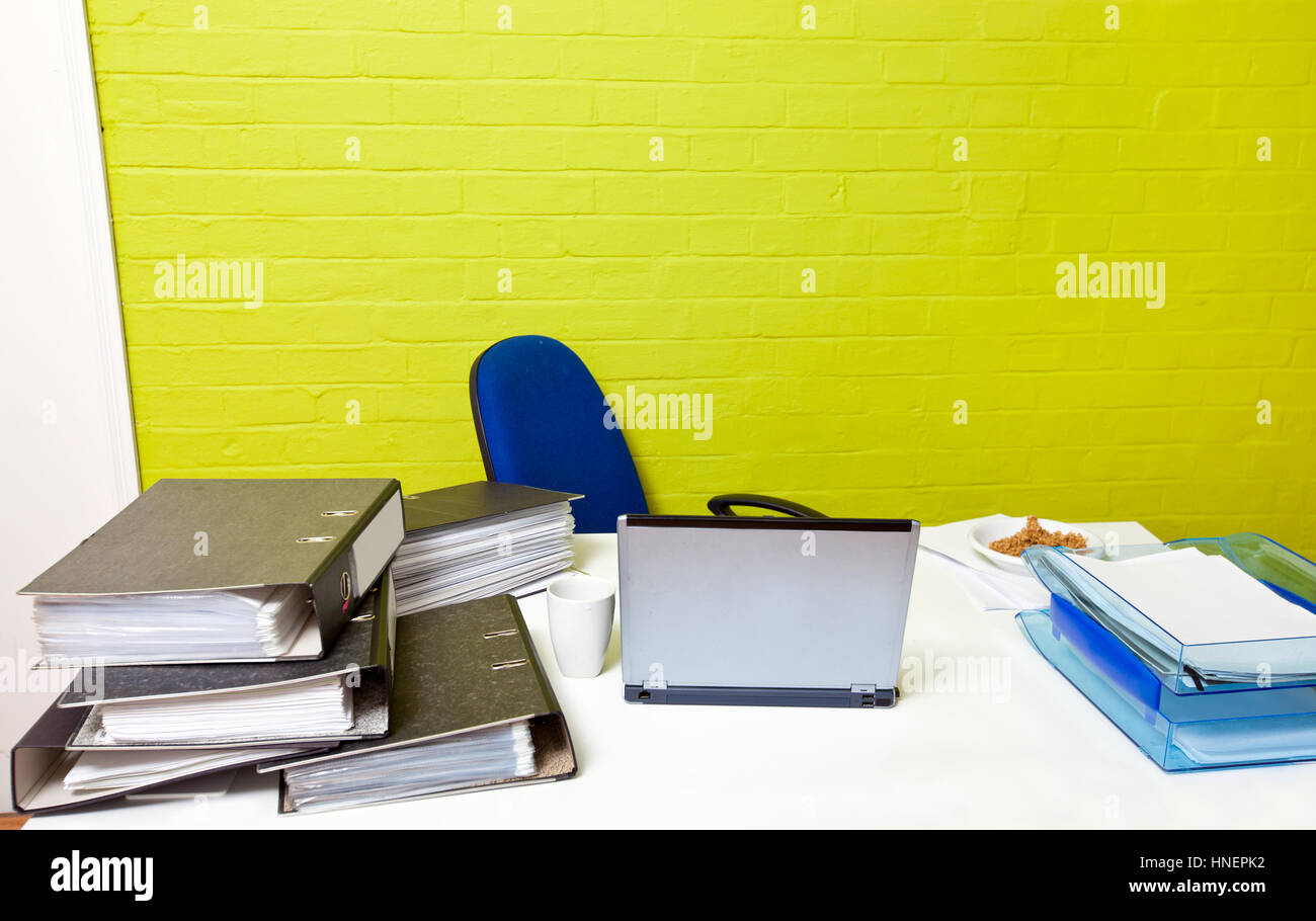 Vacante scrivania con computer portatile, cartelle e sedia vuota Foto Stock