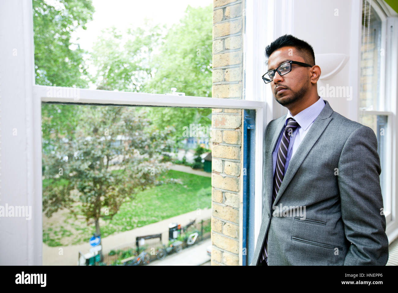 Ritratto di commerciante indiano con gli occhiali in piedi dalla finestra Foto Stock
