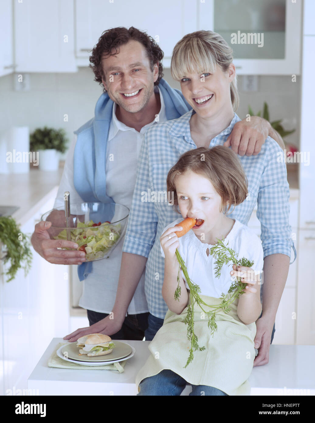 Ragazza giovane mangiando la carota con i genitori Foto Stock