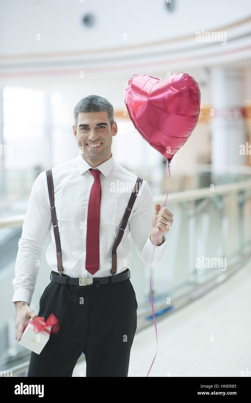 Imprenditore tenendo a forma di cuore e a palloncino presente Foto Stock
