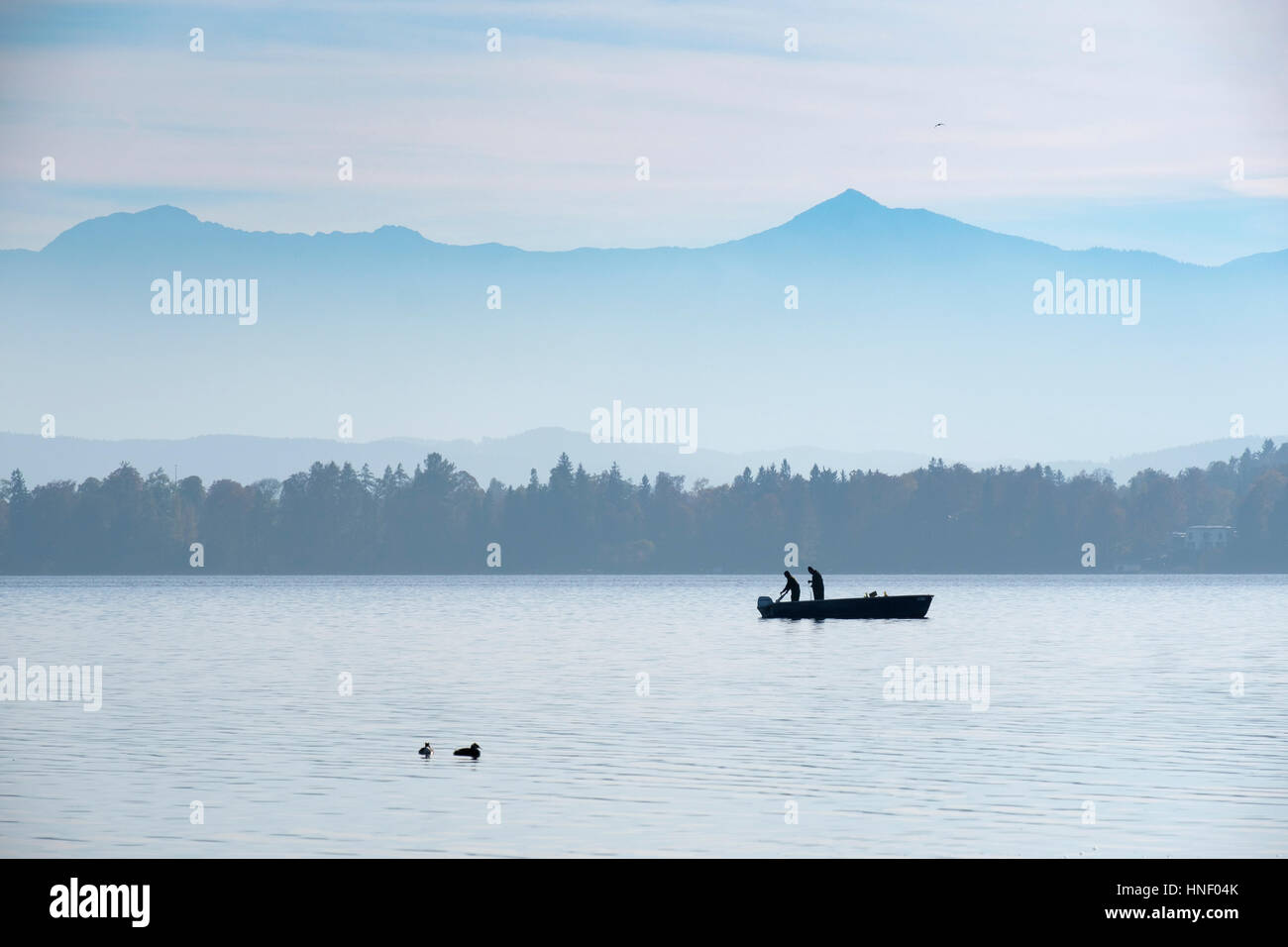 Pescatore in barca, il lago di Starnberg con Alpi, Bernried, Fünfseenland, Alta Baviera, Baviera, Germania Foto Stock