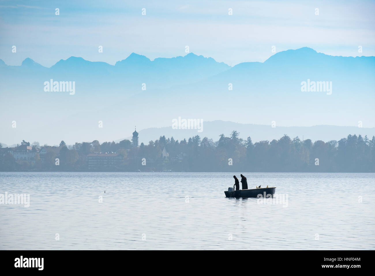 Pescatore in barca, il lago di Starnberg con Alpi, Seeshaupt, Fünfseenland, Alta Baviera, Baviera, Germania Foto Stock