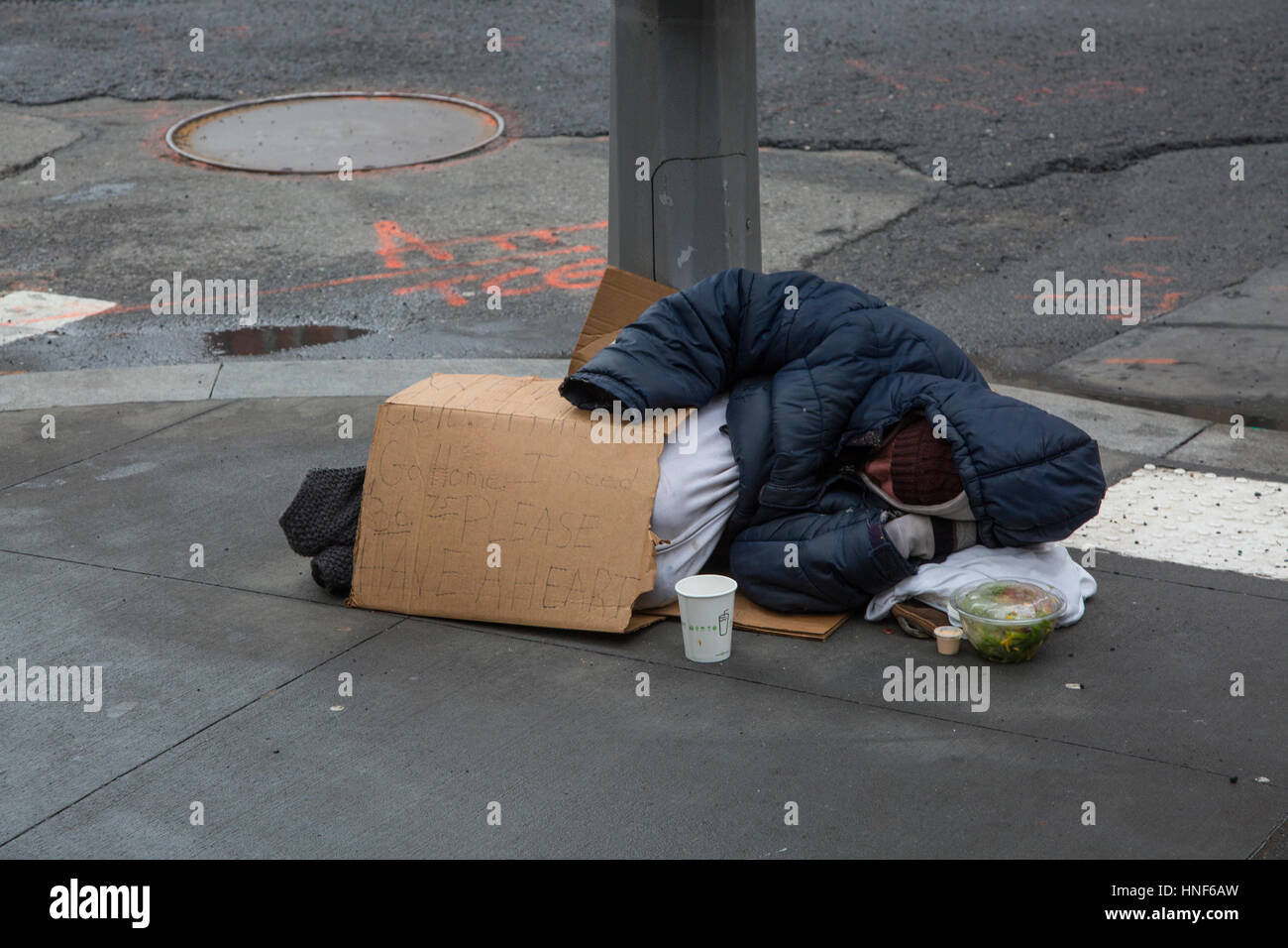 La persona senza dimora prono sul marciapiede per l'accattonaggio denaro su Broadway nel centro cittadino di Manhattan, New York. Foto Stock