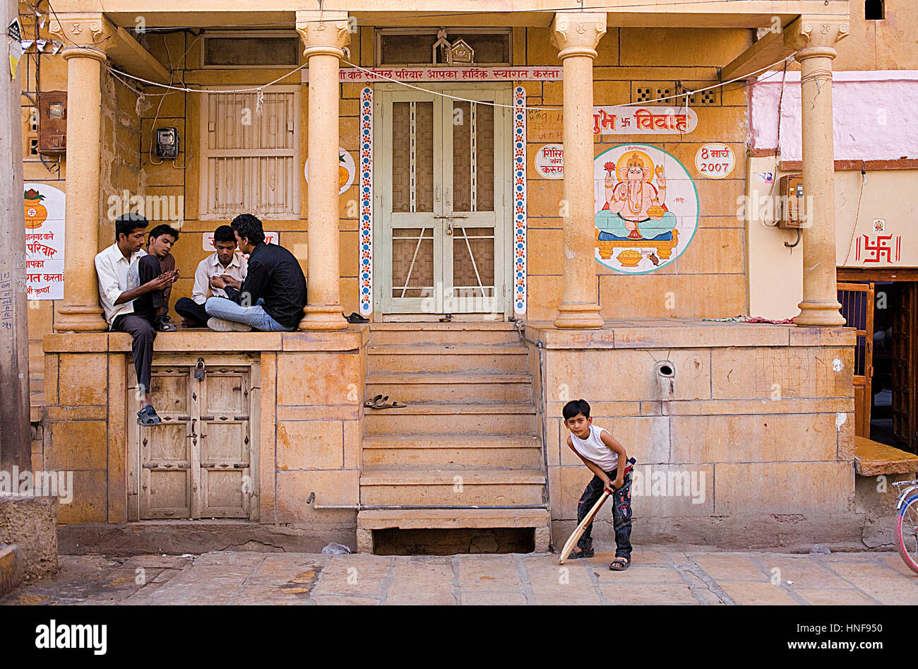 L'uomo giocando a carte e ragazzo giocando a cricket, Street scene,Jaisalmer, Rajasthan, India Foto Stock