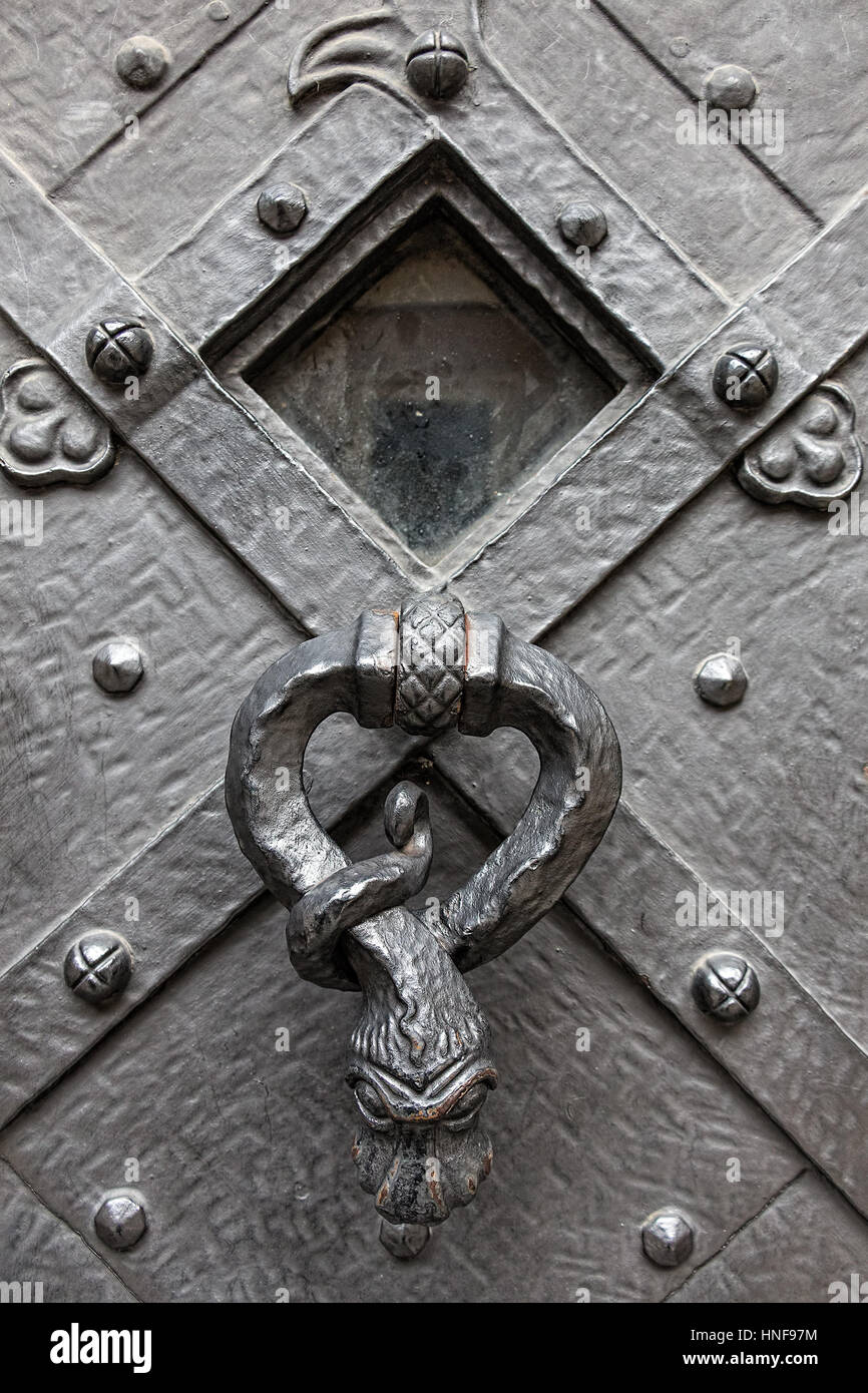 Vecchio e storico di elementi in ferro battuto, porta di metallo dalla vecchia cattedrale con il rapper decorativo, respingente. Fondo di architettura. Foto Stock