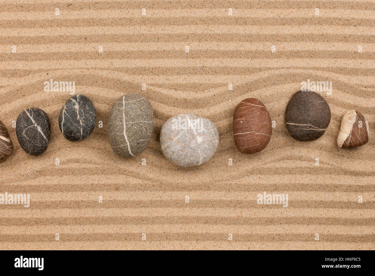Una fila di pietre distesi sulla sabbia, con spazio per il testo. Vista da sopra Foto Stock