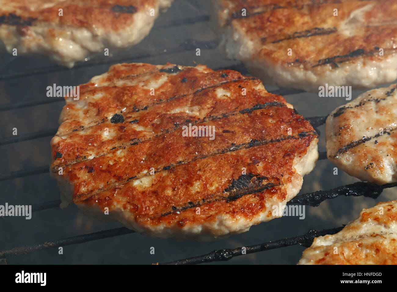 Un pollo o tacchino pollame carni grigliate barbecue burger per hamburger preparati sul fumo barbecue grill, close up Foto Stock