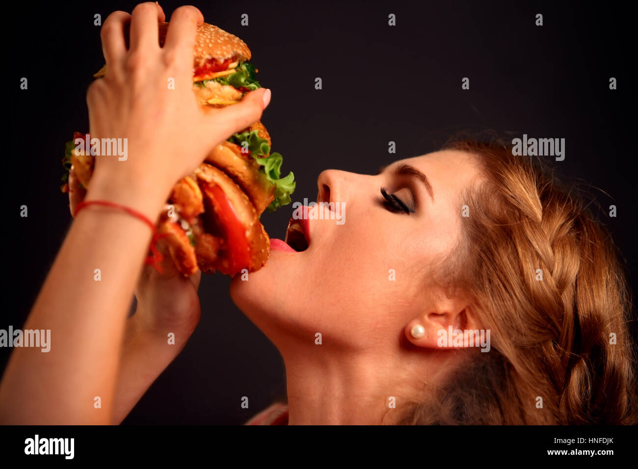 Donna di mangiare hamburger. Studente consumano fast food. Foto Stock