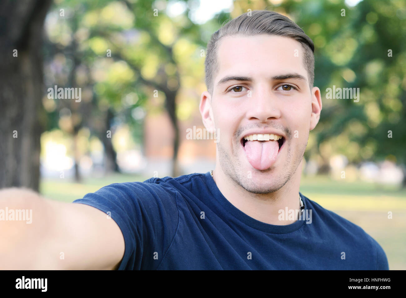 Giovane uomo latino tenendo un selfie in un parco. All'esterno. Foto Stock