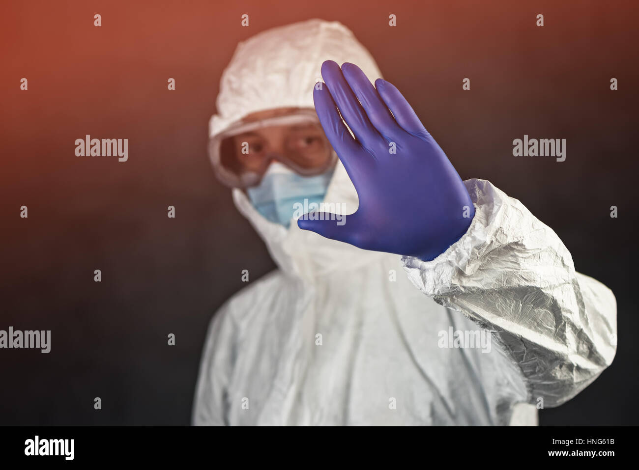 Scienziato medico di indossare abbigliamento protettivo e vetreria gesticolando segno di stop in quarantena Foto Stock