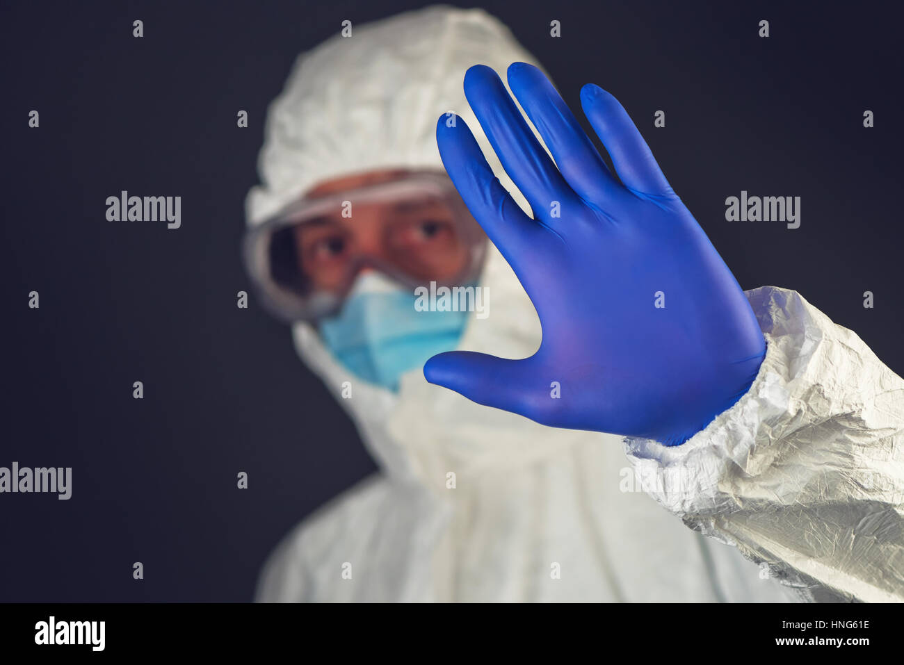 Scienziato medico di indossare abbigliamento protettivo e vetreria gesticolando segno di stop in quarantena Foto Stock