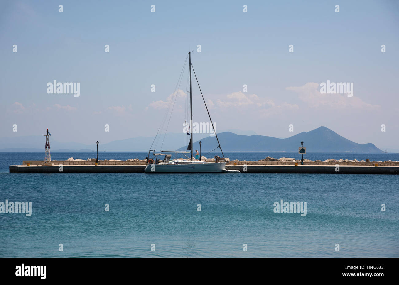 Vista sul molo e la vela boa in Frikes Harbour, sull'isola di Itaca in Grecia, con l'isola di Atokos in background Foto Stock
