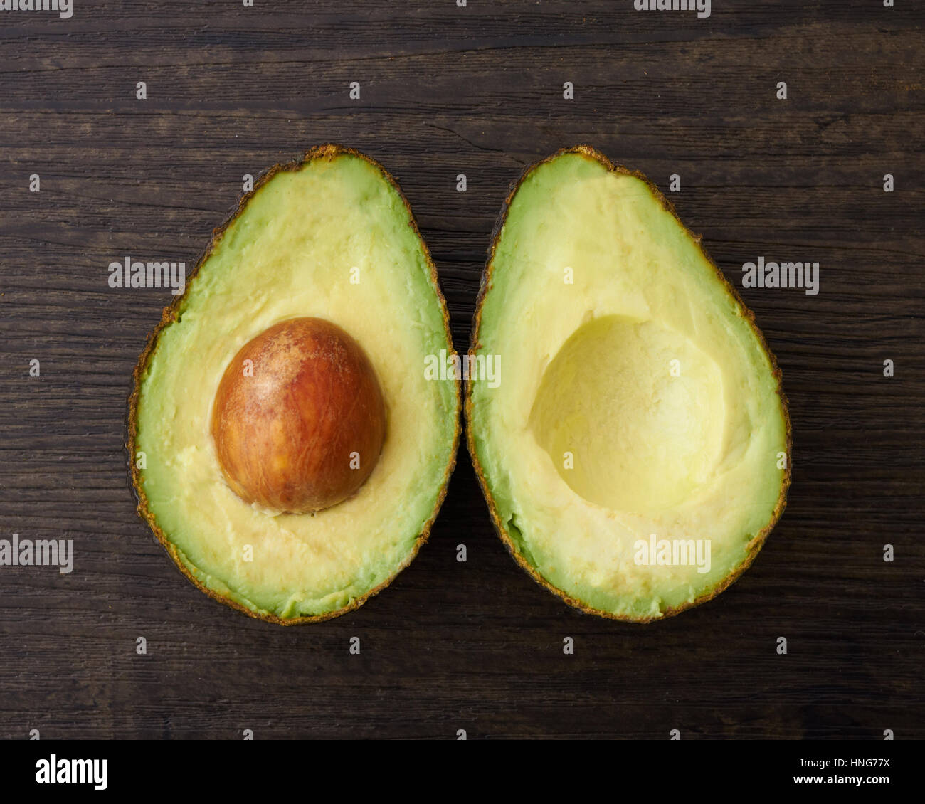 Due metà di un taglio avocado su di una superficie di legno Foto Stock