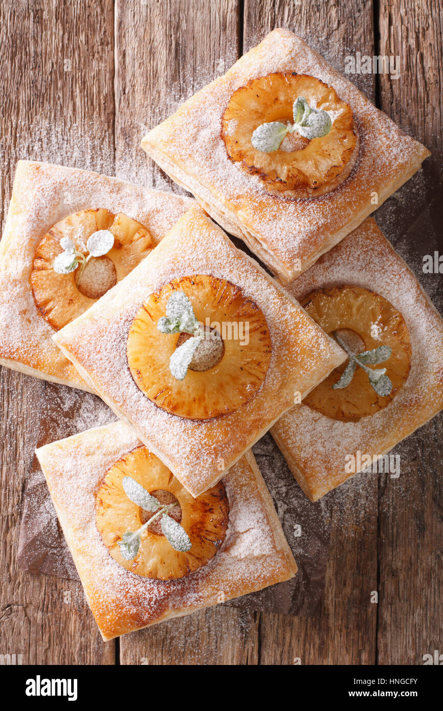 Pasta sfoglia torta con ananas e decorate con la menta e lo zucchero in polvere di close-up sul tavolo. vista verticale da sopra Foto Stock