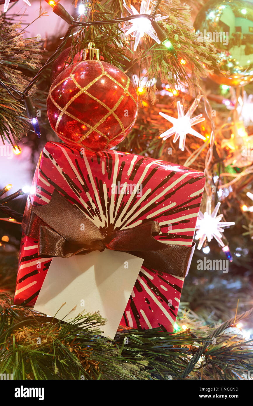 Confezione regalo sotto albero di Natale colorate luci della sera Foto Stock