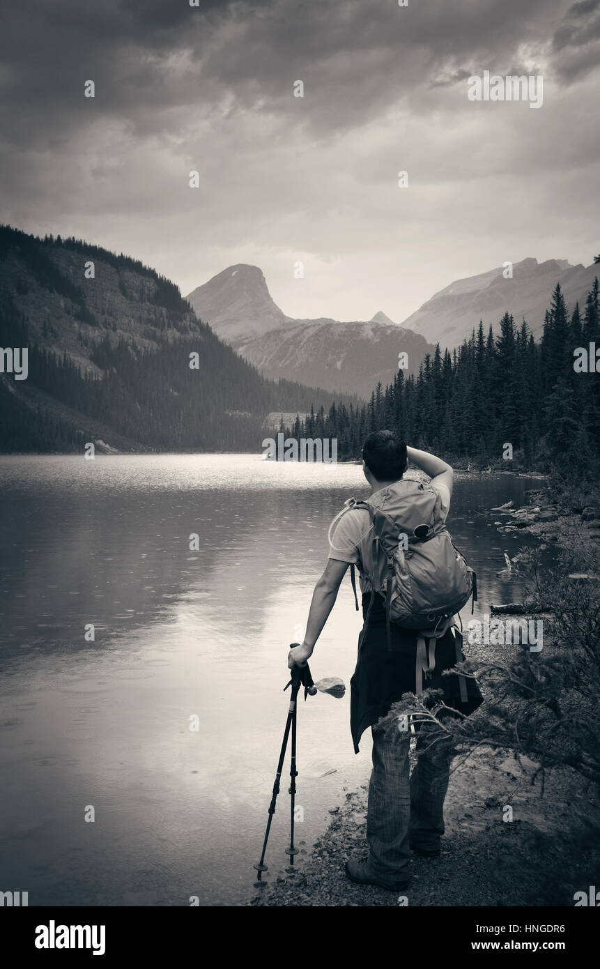 Escursionista riposo a lato del lago in un giorno di pioggia con foreste di montagna e cloud. Foto Stock