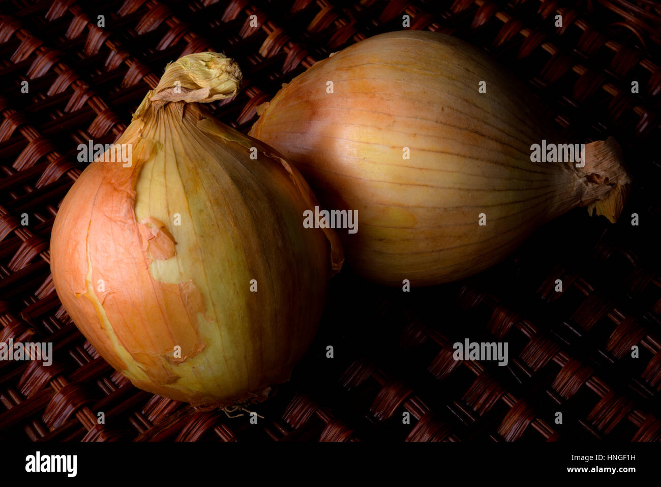 Due cipolle dorate sul tavolo di vimini Foto Stock