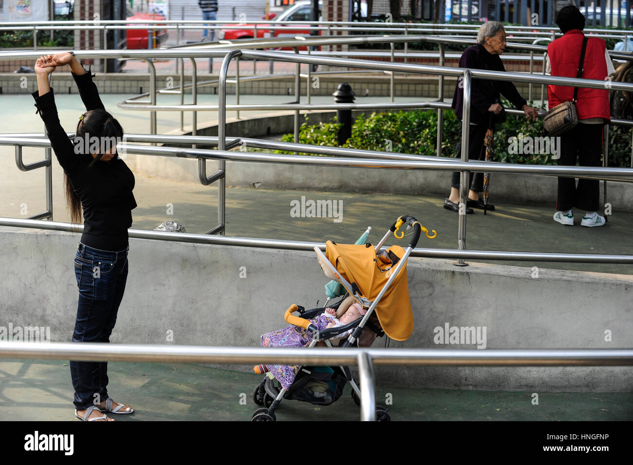 Cina, Megacity di Hong Kong, Kowloon, persone facendo esercizio in parco pubblico, il bambino nel seggiolone carro Foto Stock