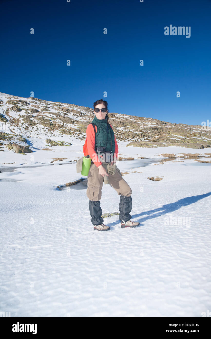 Bruna sport active donna con giubbotto verde, maglione rosso, marrone Pantaloni  trekking a piedi nella neve con il cielo azzurro in Gredos mountain, Avila,  Spagna, Europa Foto stock - Alamy