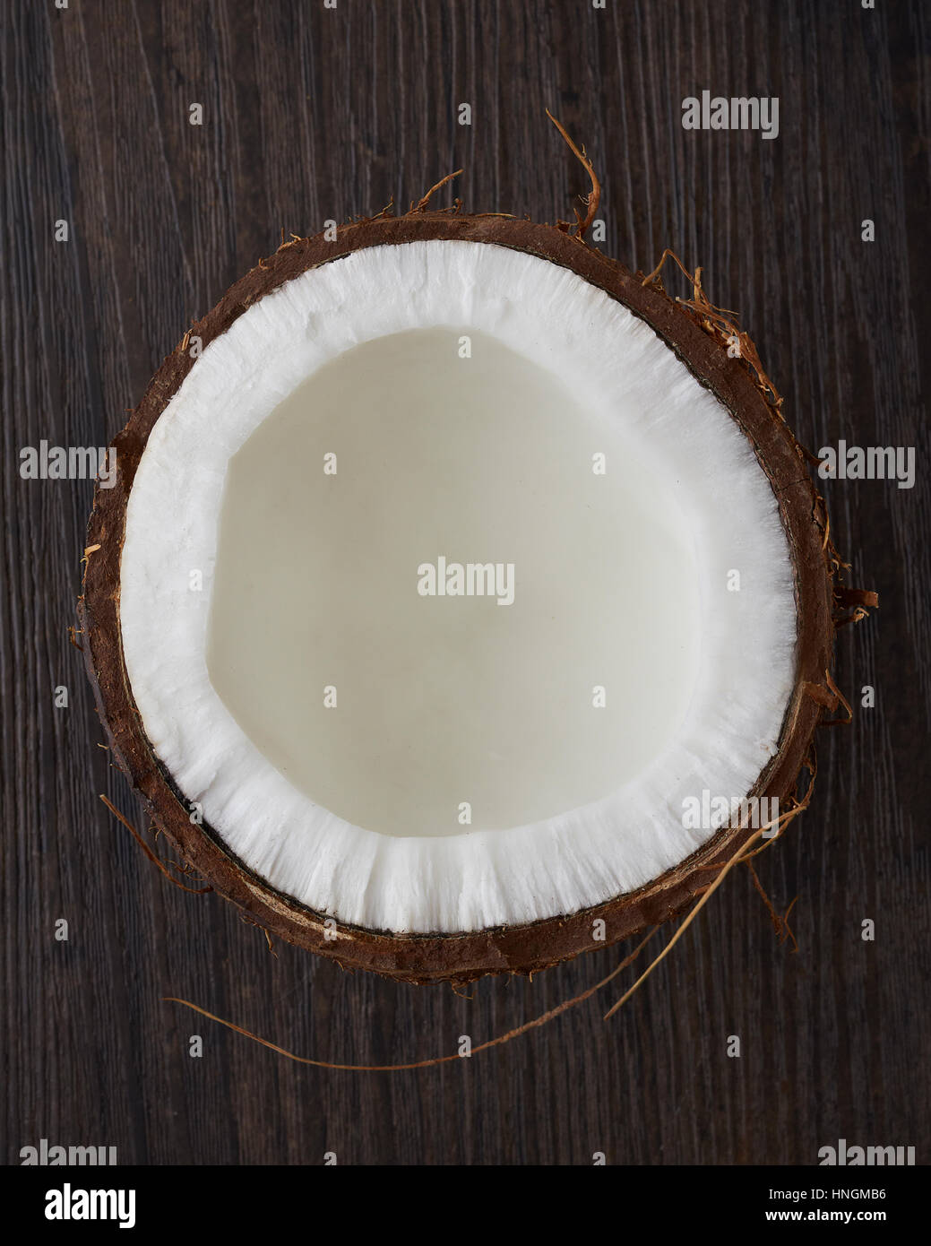 Close up di un cocco fresco per metà su un legno scuro dello sfondo. Foto Stock