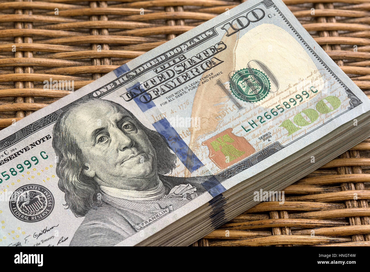 Pila di Stati Uniti d'America USD 100 di un centinaio di dollari Federal Reserve Note pila su sfondo di vimini Foto Stock
