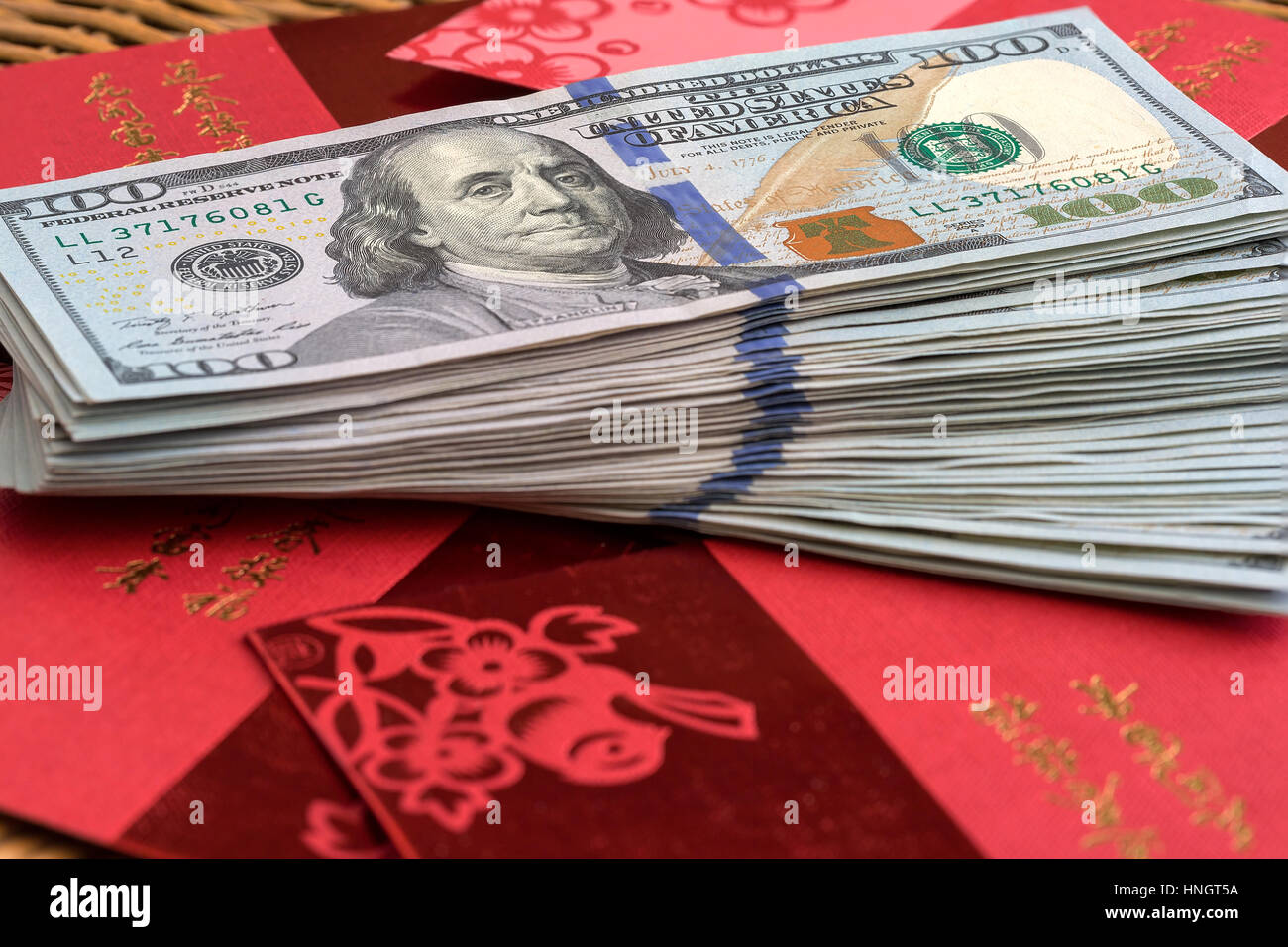 Pila di USD un centinaio di dollari note su top pacchetti rosso con testo in cinese che desiderano la ricchezza e la felicità per il nuovo anno lunare cinese Foto Stock