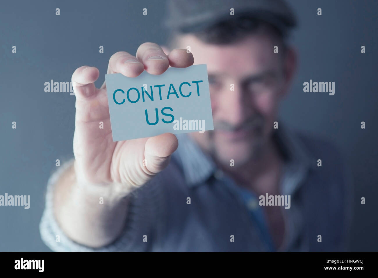 Uomo con in mano una carta con le parole Contattaci Foto Stock