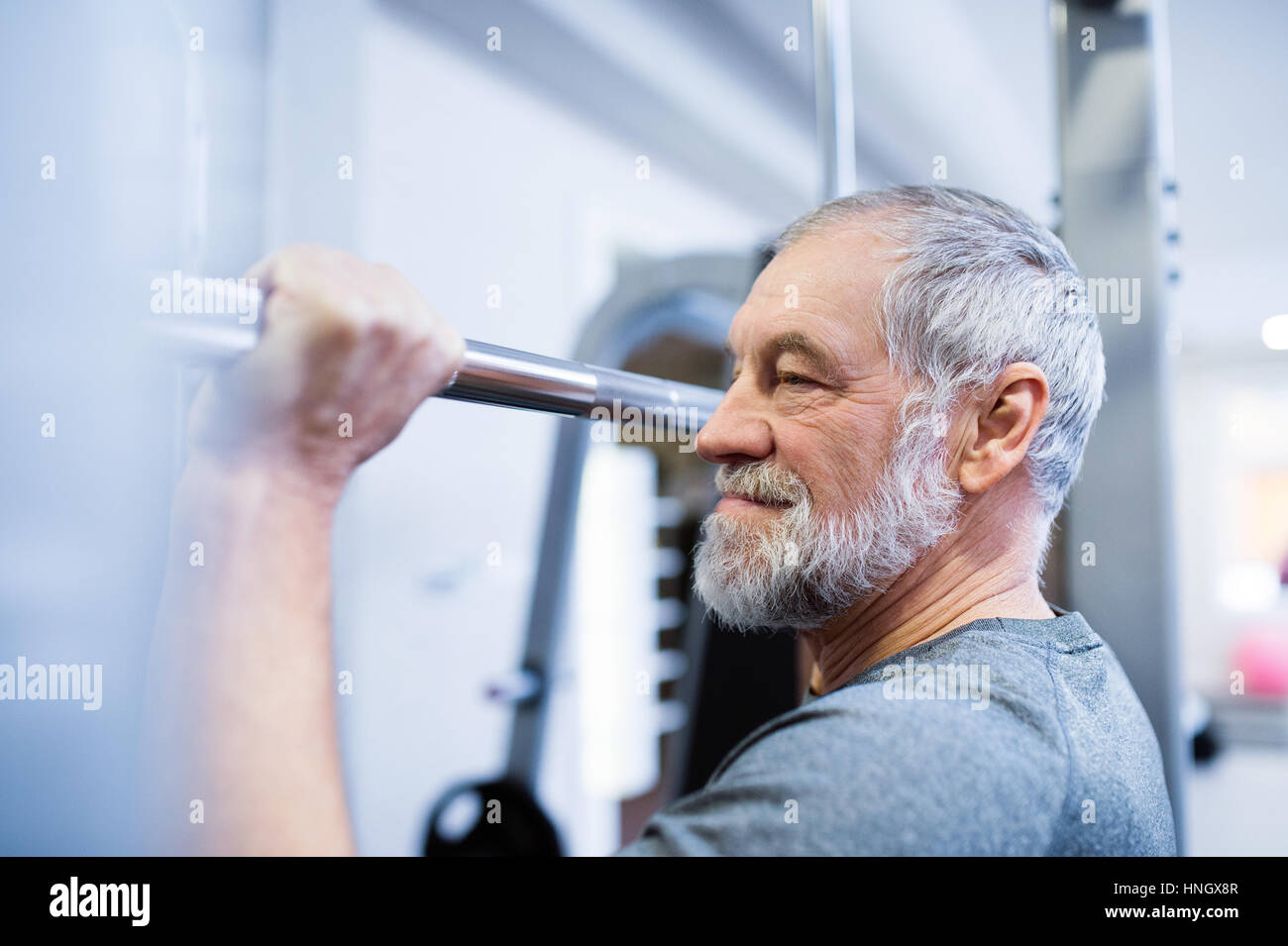 Uomo Senior in palestra facendo pull-ups sulla barra orizzontale. Foto Stock
