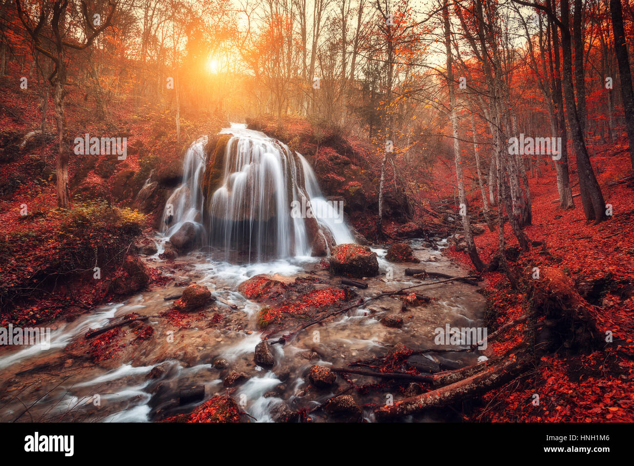 Cascata. Paesaggio colorato con bella cascata al fiume di montagna nella foresta con fogliame rosso al tramonto in autunno. Alberi con foglie rosse. St Foto Stock