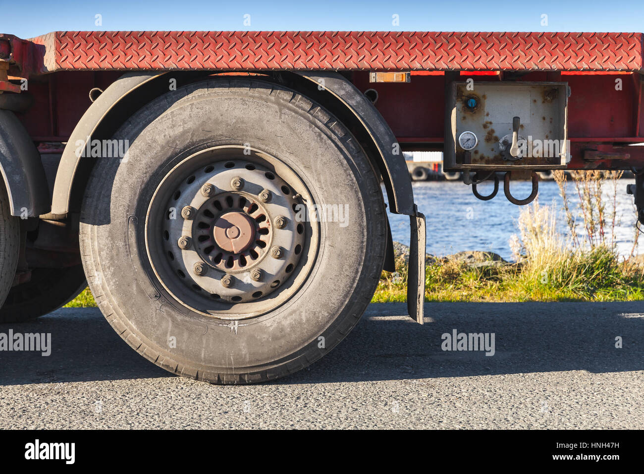 Frammento di camion Cargo, rimorchio rosso ruota su strada asfaltata Foto Stock