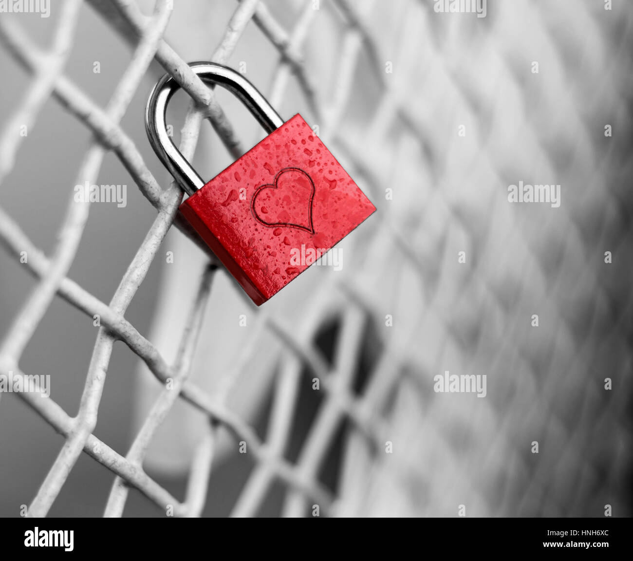 Colorato di rosso il lucchetto con una incisione di cuore attaccato al recinto che simboleggia l'amore e l'amicizia Foto Stock