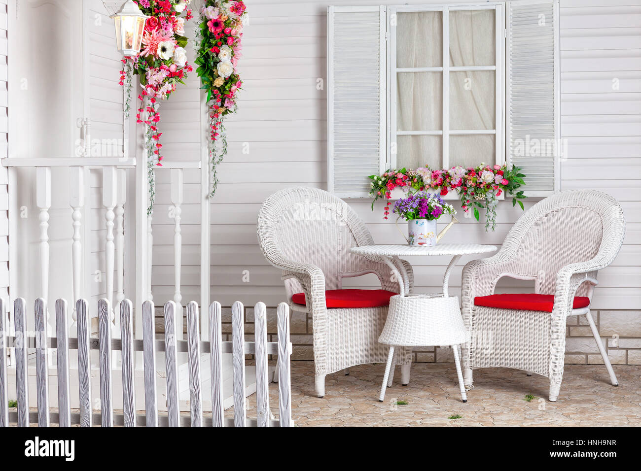 White country house in stile provenzale decorato con fiori. La residenza estiva e un luogo per rilassarsi con mobili di vimini. Foto Stock
