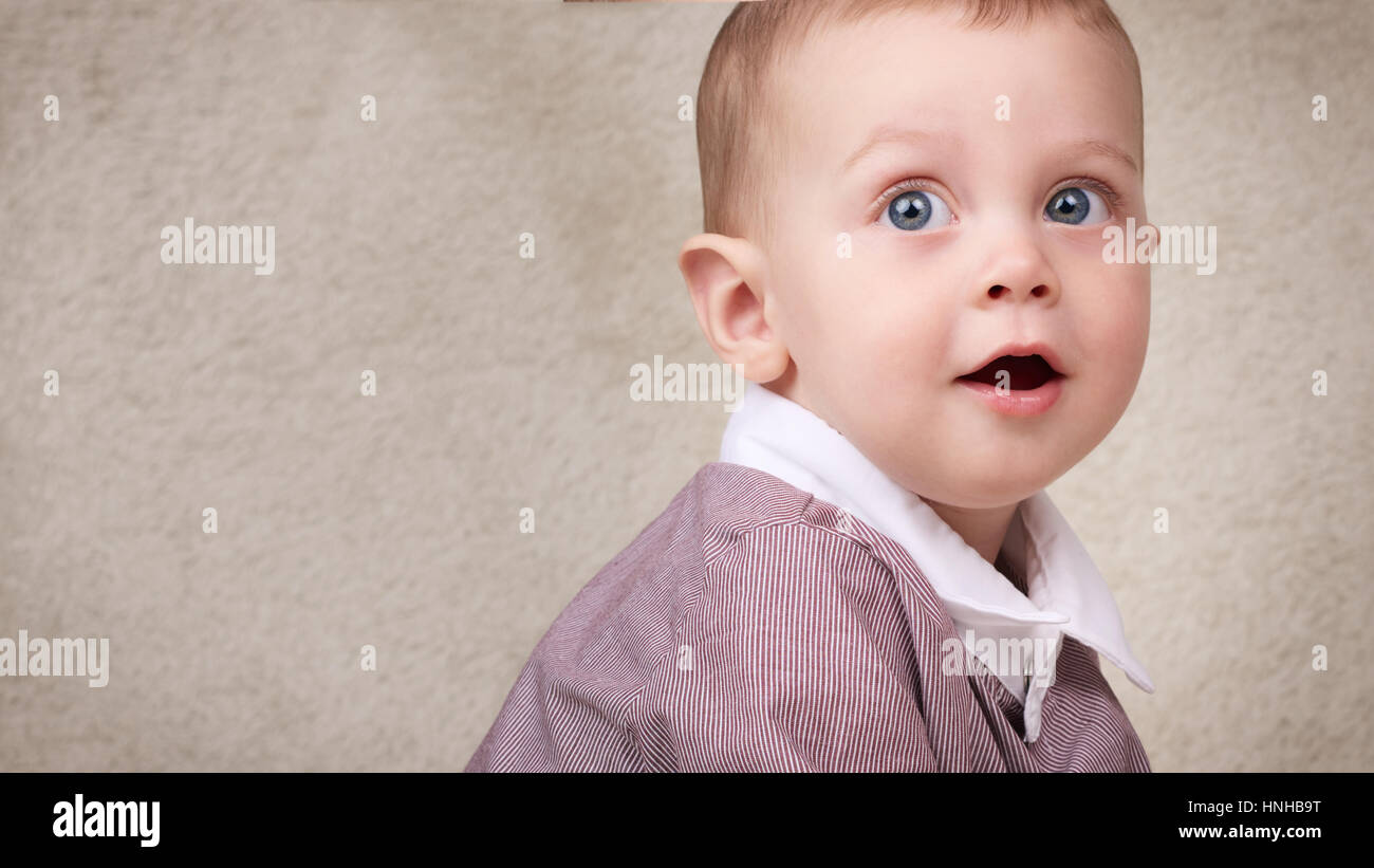 Baby boy guardando sopra la sua spalla con graziosi espressione facciale Foto Stock