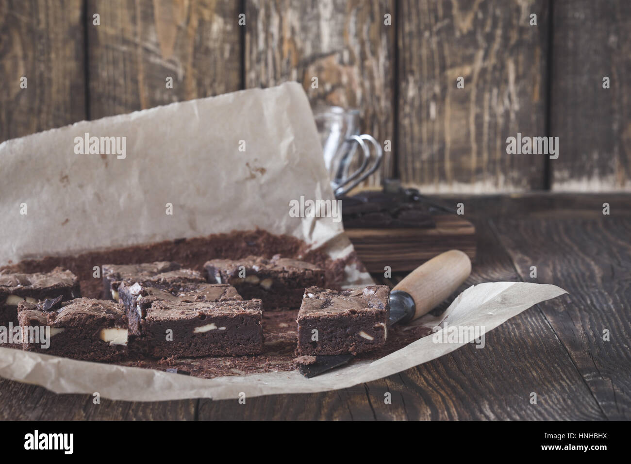 In casa dark brownie al cioccolato con crema di formaggio sulla carta da forno su tavola in legno rustico Foto Stock