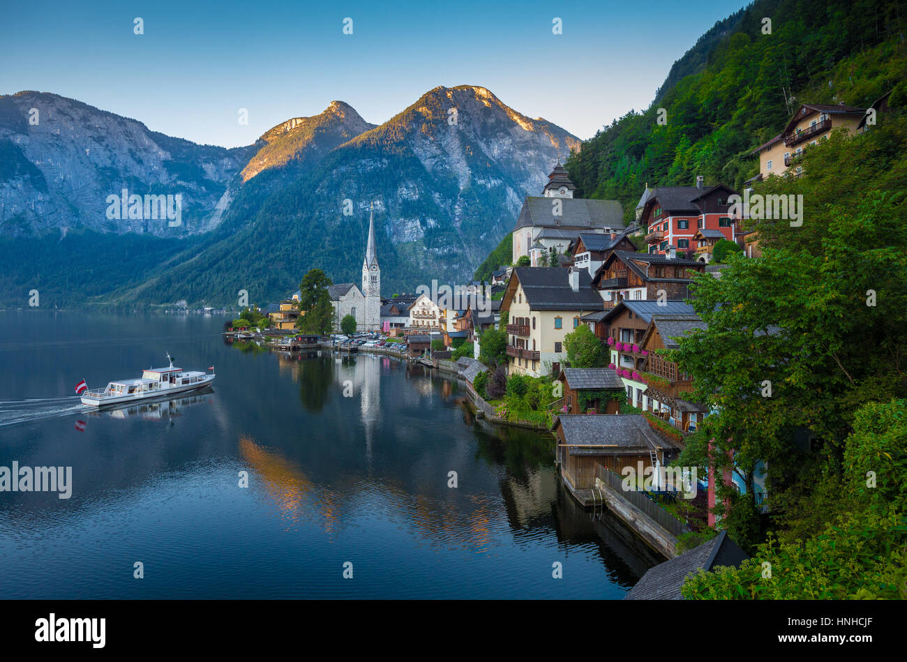 Classic vista da cartolina famosa Hallstatt Lakeside Town nelle Alpi con tradizionale nave passeggeri in bella mattina presto luce all'alba, Austria Foto Stock