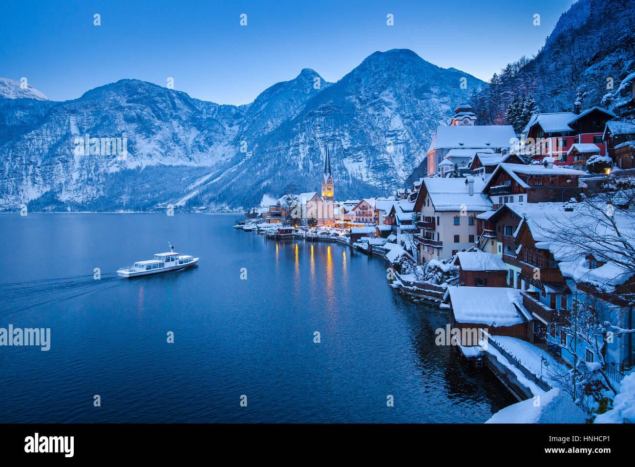 Classic vista da cartolina famosa Hallstatt Lakeside Town nelle Alpi con tradizionale nave passeggeri in inverno mistica twilight, Salzkammergut, Austria Foto Stock