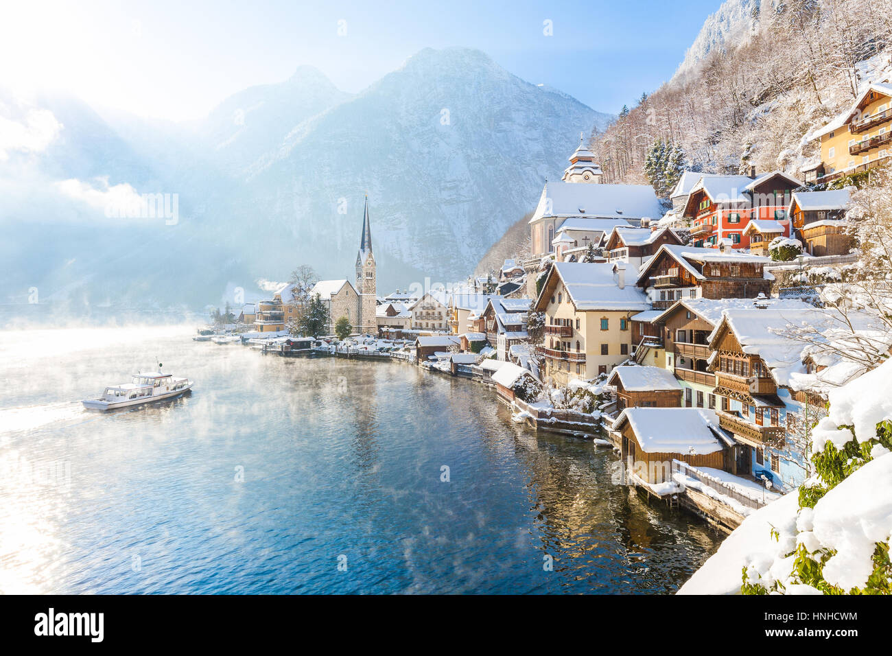 Classic vista da cartolina famosa Hallstatt Lakeside Town nelle Alpi con nave passeggeri su una bella giornata di sole con cielo blu e nuvole in inverno Foto Stock