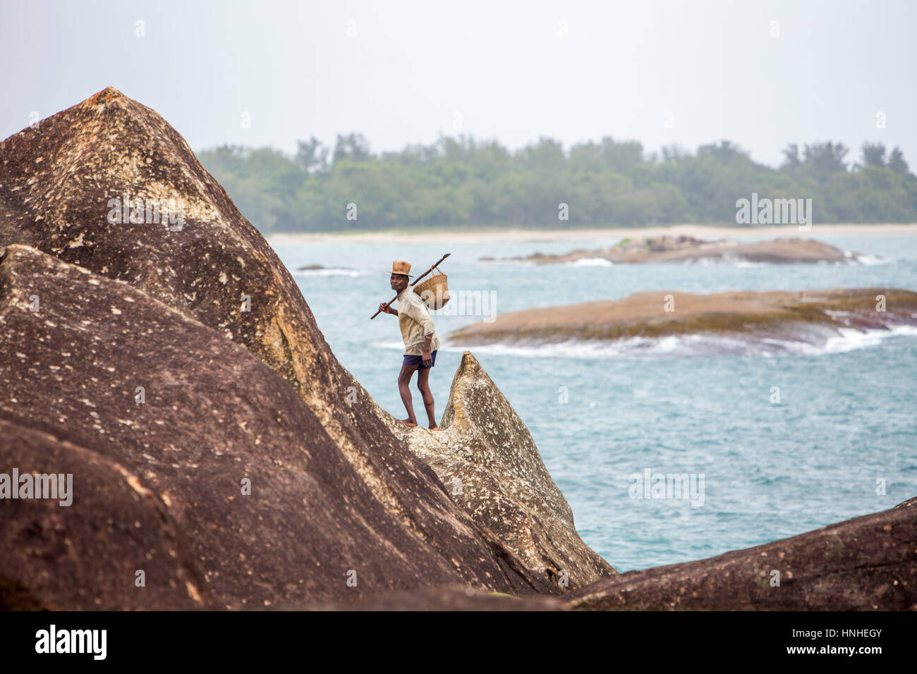 Il vecchio uomo di ritorno dal suo quotidiano di cattura - raffigurato come camminare sulle rocce giganti. Pescatore rurale delle comunità lungo la costa in area Fort-Dauphin. Foto Stock