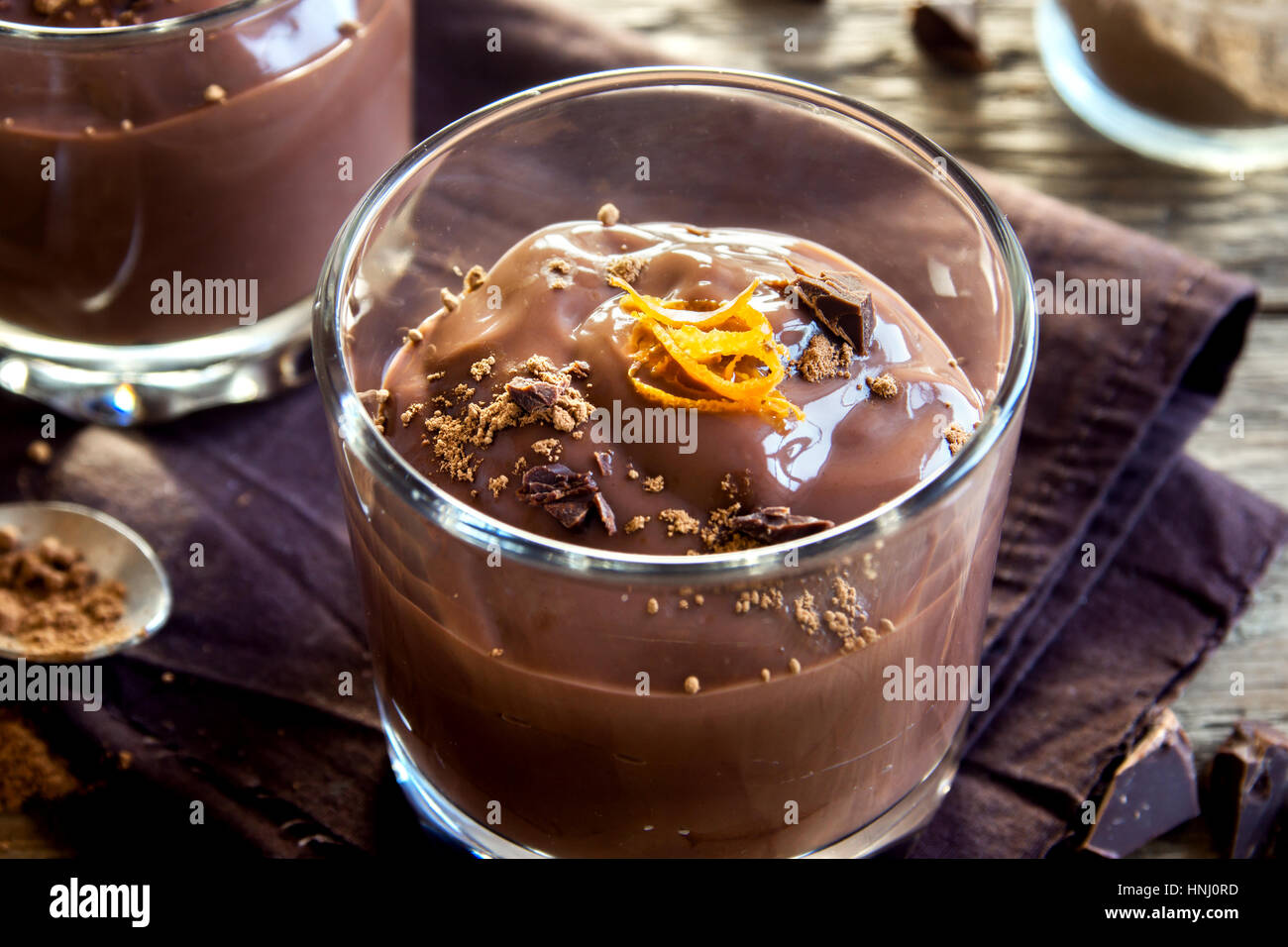 Mousse al cioccolato guarnita con scorza di arancia in bicchieri su sfondo in legno close up - deliziosa casa budino di cioccolato Foto Stock