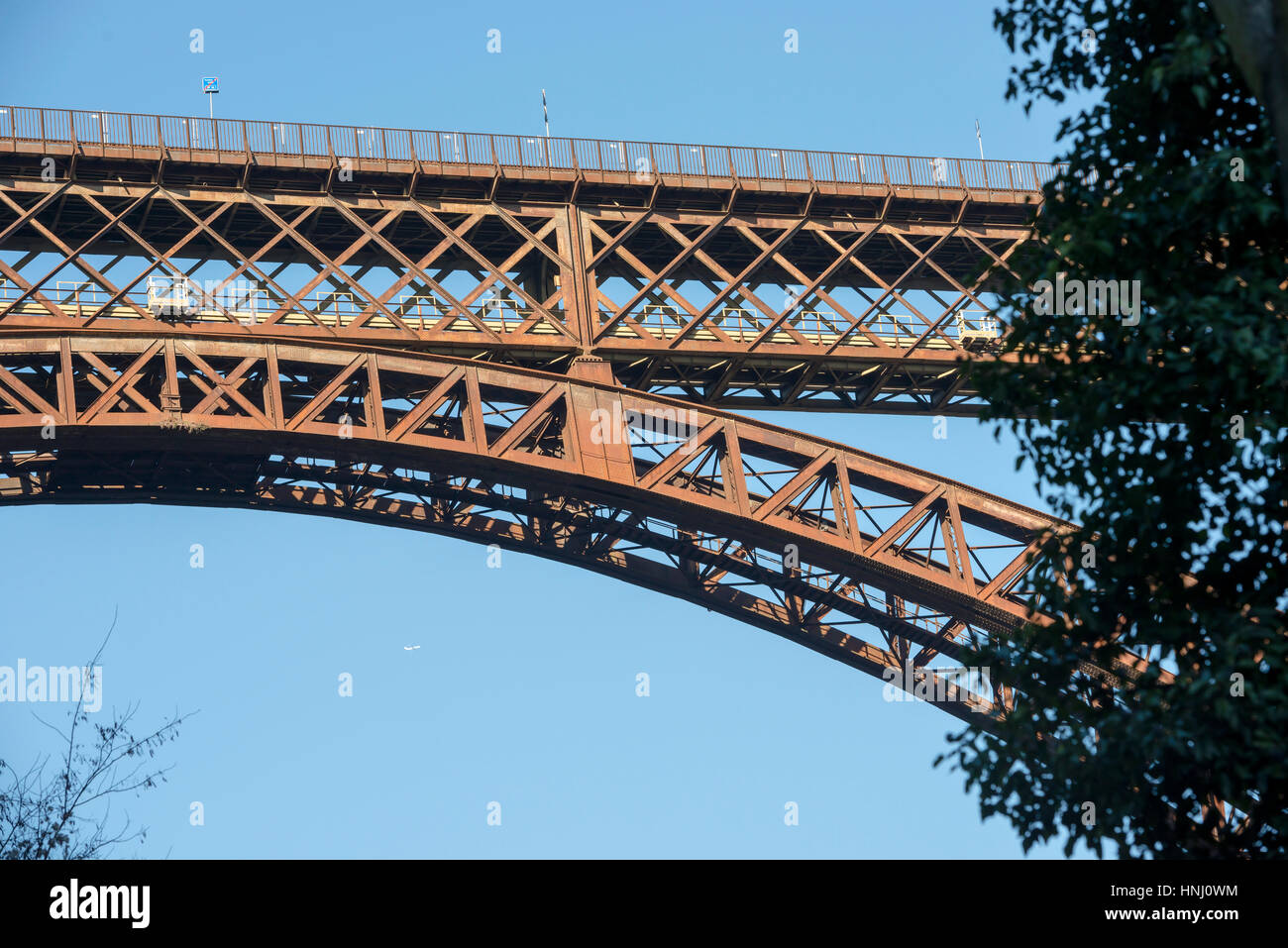 Dettaglio del trellis di ferro vecchio ponte sul fiume Adda , girato in condizioni di luce intensa a Paderno mentre in distanza un getto rivestimento passa da, Lombardia, Italia Foto Stock