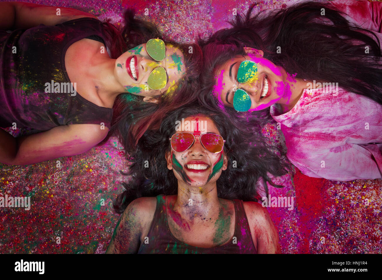 Elevato angolo di visione indiana di ragazze adolescenti giacenti e coperto di polvere colorata durante Holi festival a colori Foto Stock