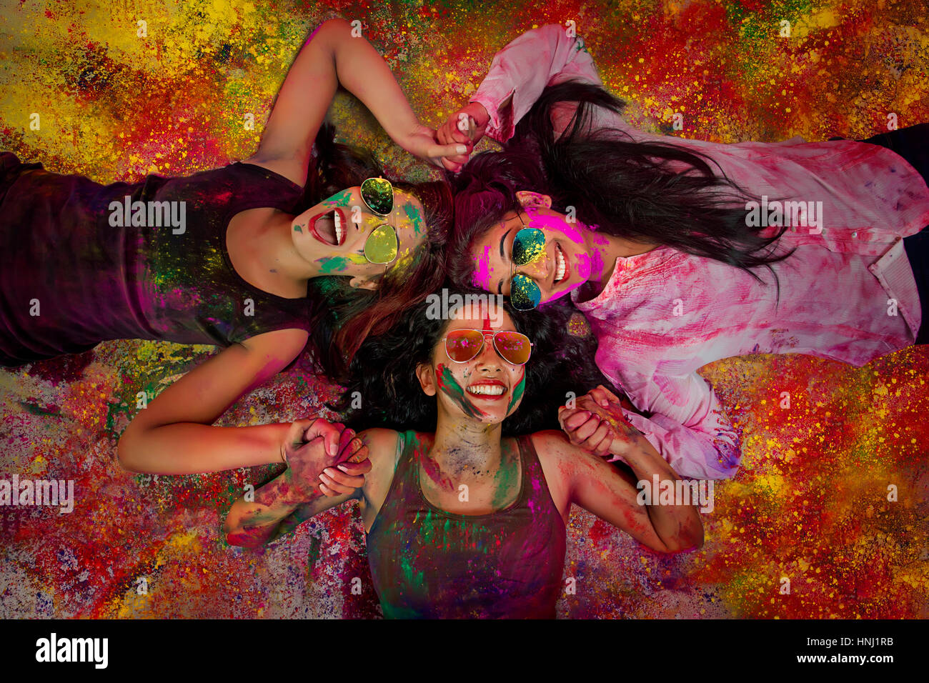 Elevato angolo di visione indiana di ragazze adolescenti giacenti e coperto di polvere colorata durante Holi festival a colori Foto Stock