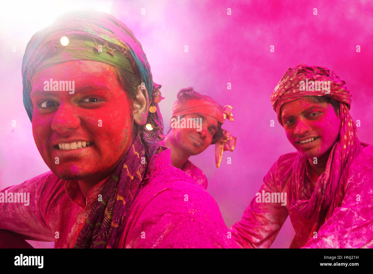 Giovani indiani uomini seduti sul pavimento coperto di polvere colorata durante Holi festival a colori Foto Stock