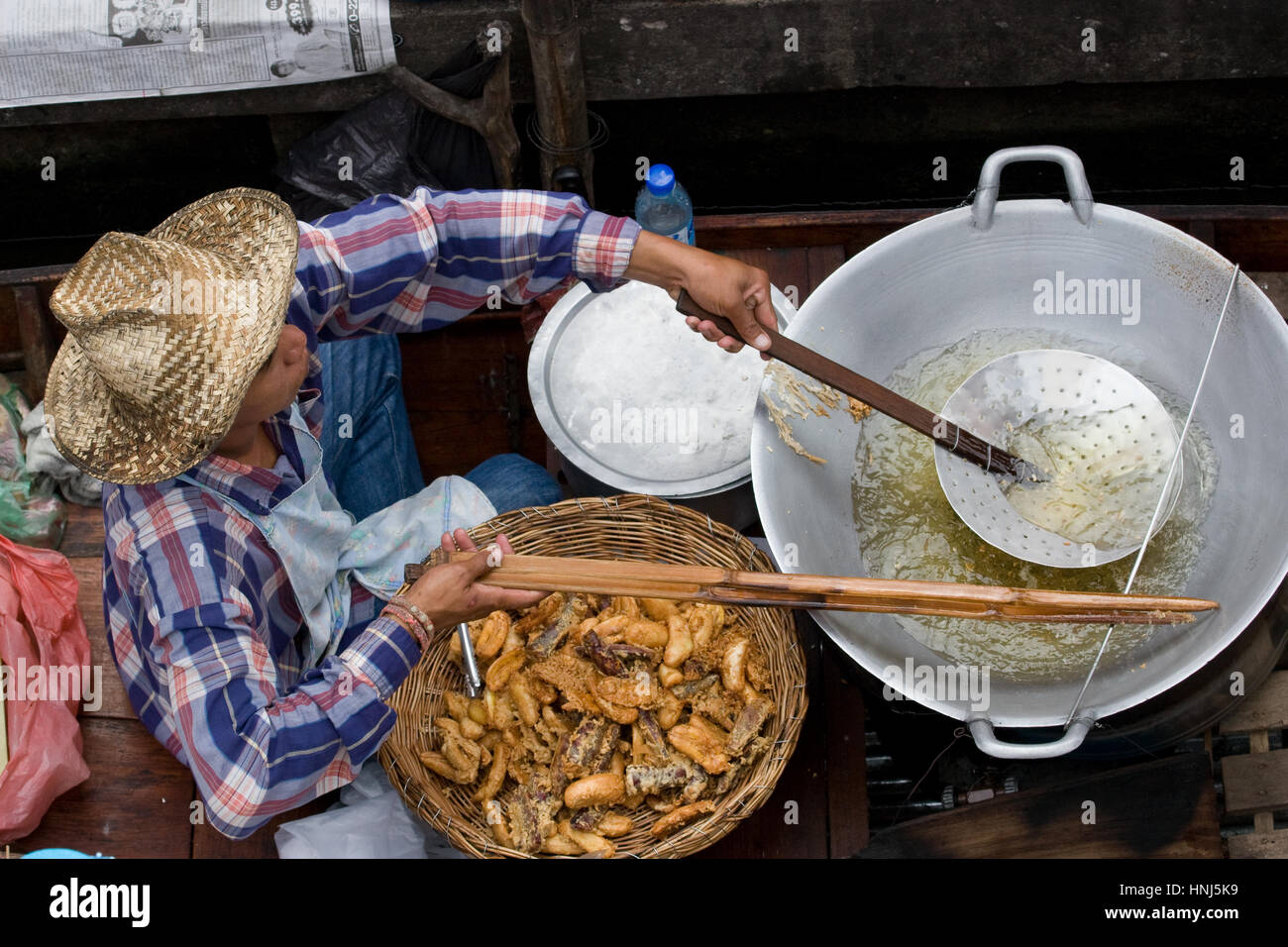 Thai uomo sulla barca vendita di pollo fritto cibo in Damnoen Saduak tradizionale mercato galleggiante della Tailandia del sud-est asiatico Foto Stock