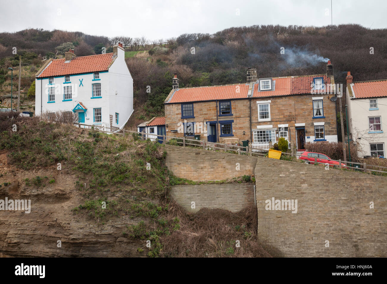 Le case su di una ripida collina che conduce in Staithes, North Yorkshire, Inghilterra,UK con fumo proveniente da camini Foto Stock