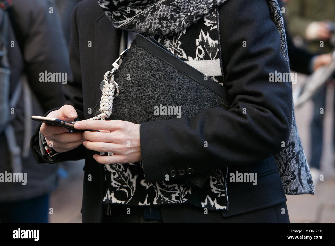 L'uomo con il nero Louis Vuitton borsa guardando smartphone prima di Salvatore Ferragamo fashion show, la Settimana della Moda Milanese street style nel gennaio 2017. Foto Stock