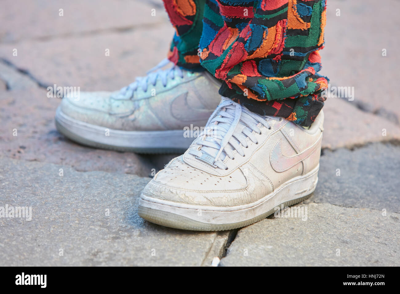 L'uomo con il bianco iridato Nike scarpe e pantaloni colorati prima di Salvatore Ferragamo fashion show, la Settimana della Moda Milanese street style. Foto Stock