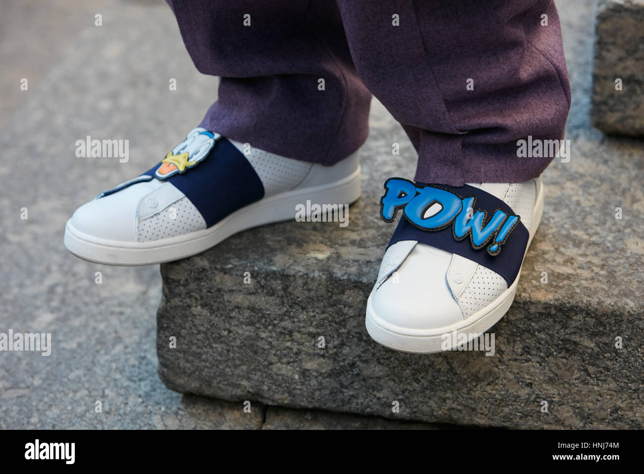 Uomo con pantaloni viola e comico iscritto Pow su bianco con le scarpe prima di Salvatore Ferragamo fashion show, la Settimana della Moda Milanese. Foto Stock