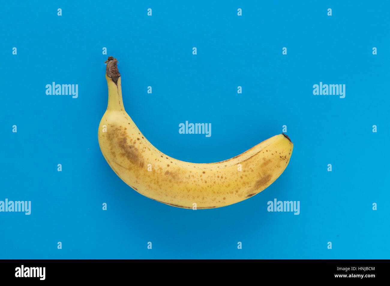 Leggermente surmature banana su sfondo azzurro. Foto Stock